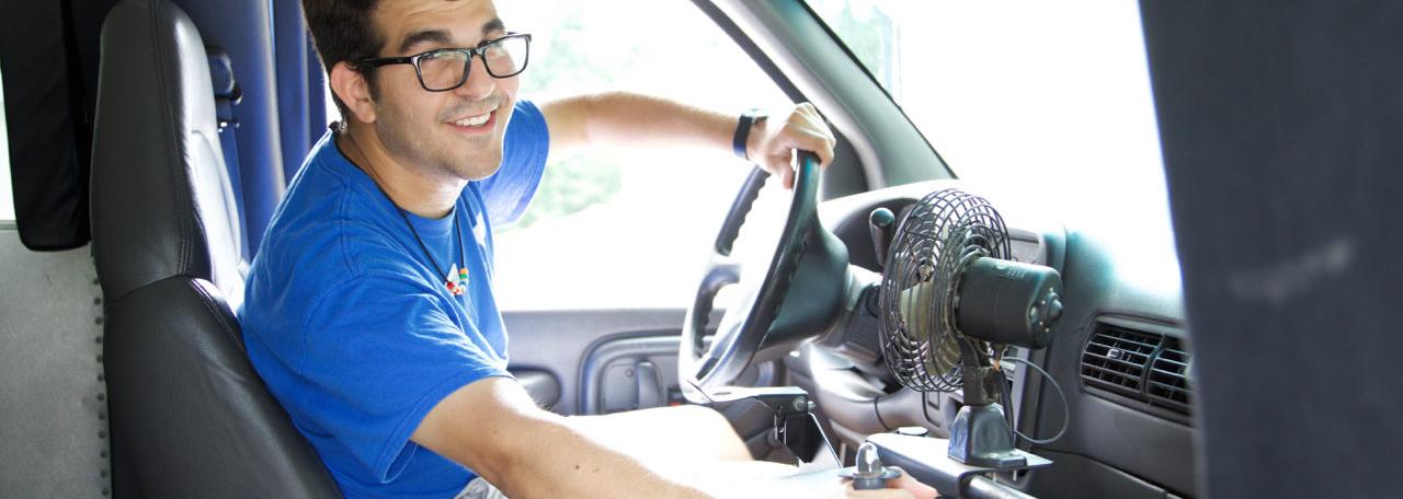 YMCA bus driver smiles as he opens the bus door