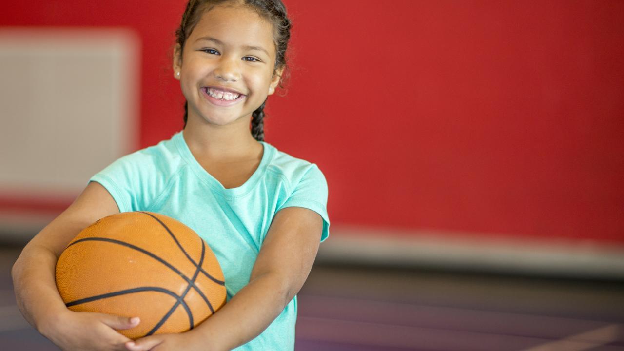 Girl Smiles with basketball Girl smiles while holding a basketball