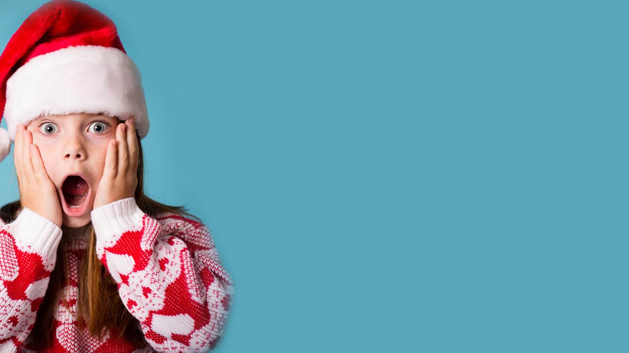 Girl in Santa hat shows surprised face