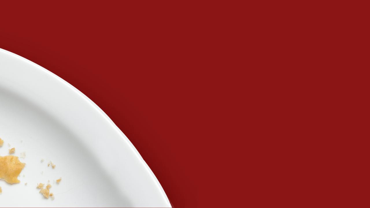 white plate with a silver fork, food crumbs against a red background