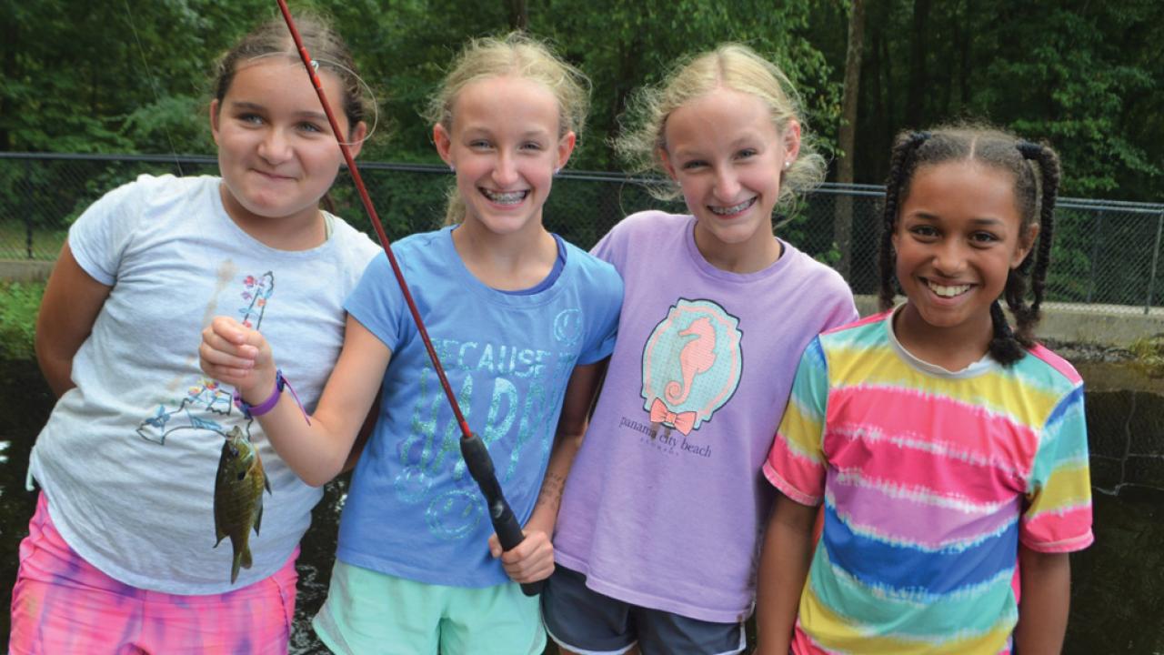 Summer Camp - Website Hero 2023 Summer Camp image with four girls fishing at Camp Thunderbird