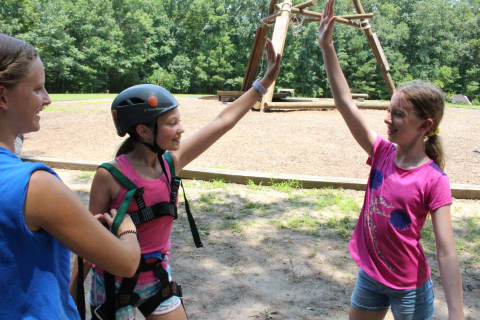 two girls high five in climbing gear