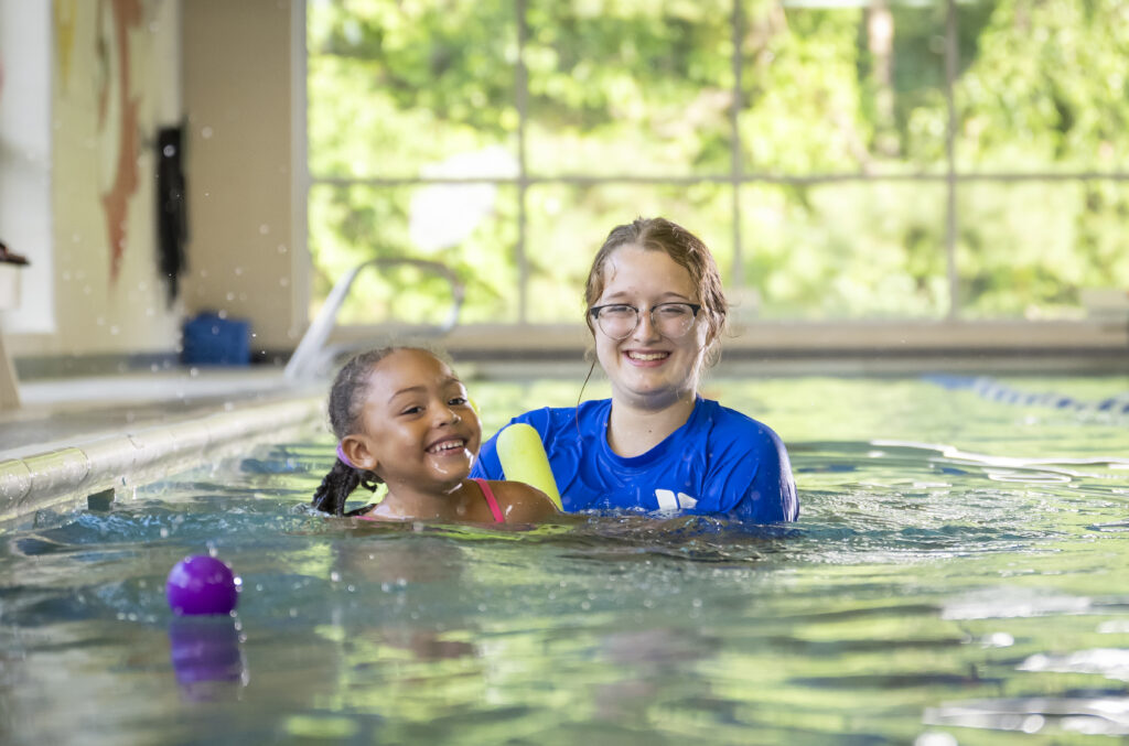 YMCA swim instructor and young girl in the pool during a lesson.